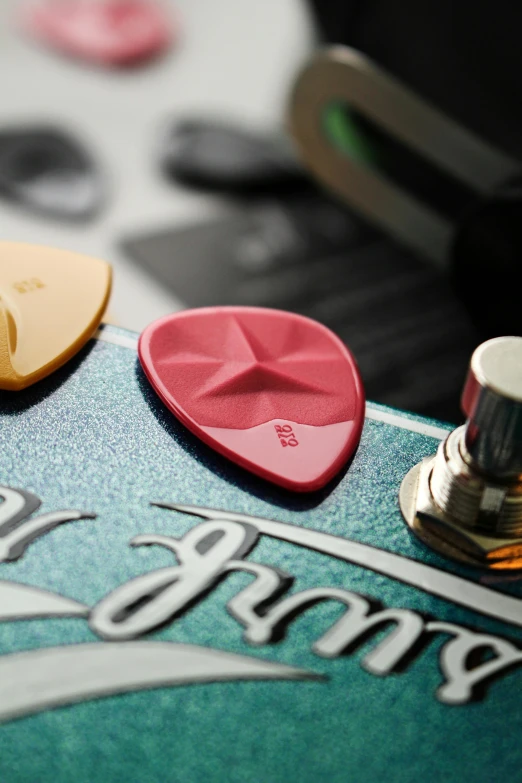 a close up of a guitar pedal on a table, by Jason Felix, pexels, pop art, viridian and venetian red, pink, high samples, kiss