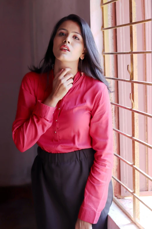 a woman standing in front of a window with her hand on her chin, inspired by T. K. Padmini, instagram, red elegant shirt, ((pink)), full body close-up shot, promo image