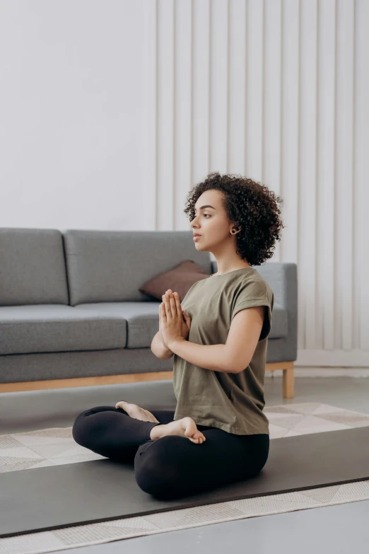 a woman sitting on a yoga mat in a living room, trending on pexels, renaissance, praying posture, square, 4 k image, 4l