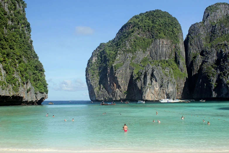 a group of people standing on top of a sandy beach, the rock is in the sea, thai architecture, swimming, two medium sized islands