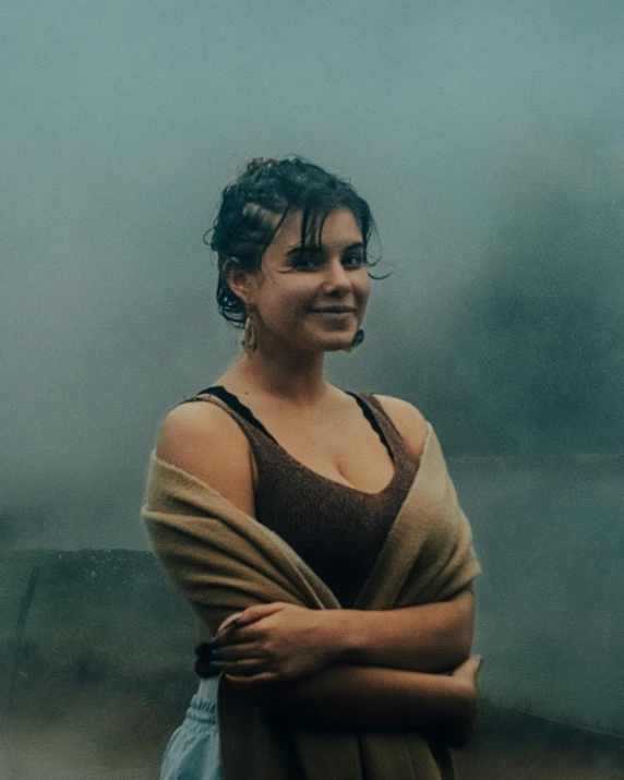 a woman standing in front of a body of water, rain and haze, isabela moner, smiling woman, grainy photo