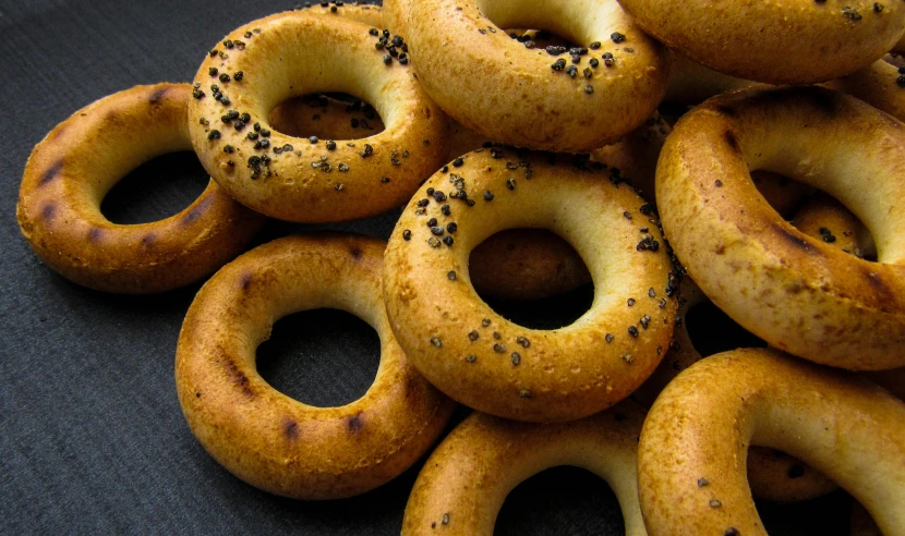 a pile of bagels sitting on top of a table, pexels, hurufiyya, yellow aureole, all enclosed in a circle, dark-skinned, gold speckles