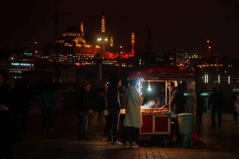 a group of people standing around a food cart, by Tobias Stimmer, pexels contest winner, hurufiyya, city lights in the background, ottoman sultan, brown, square