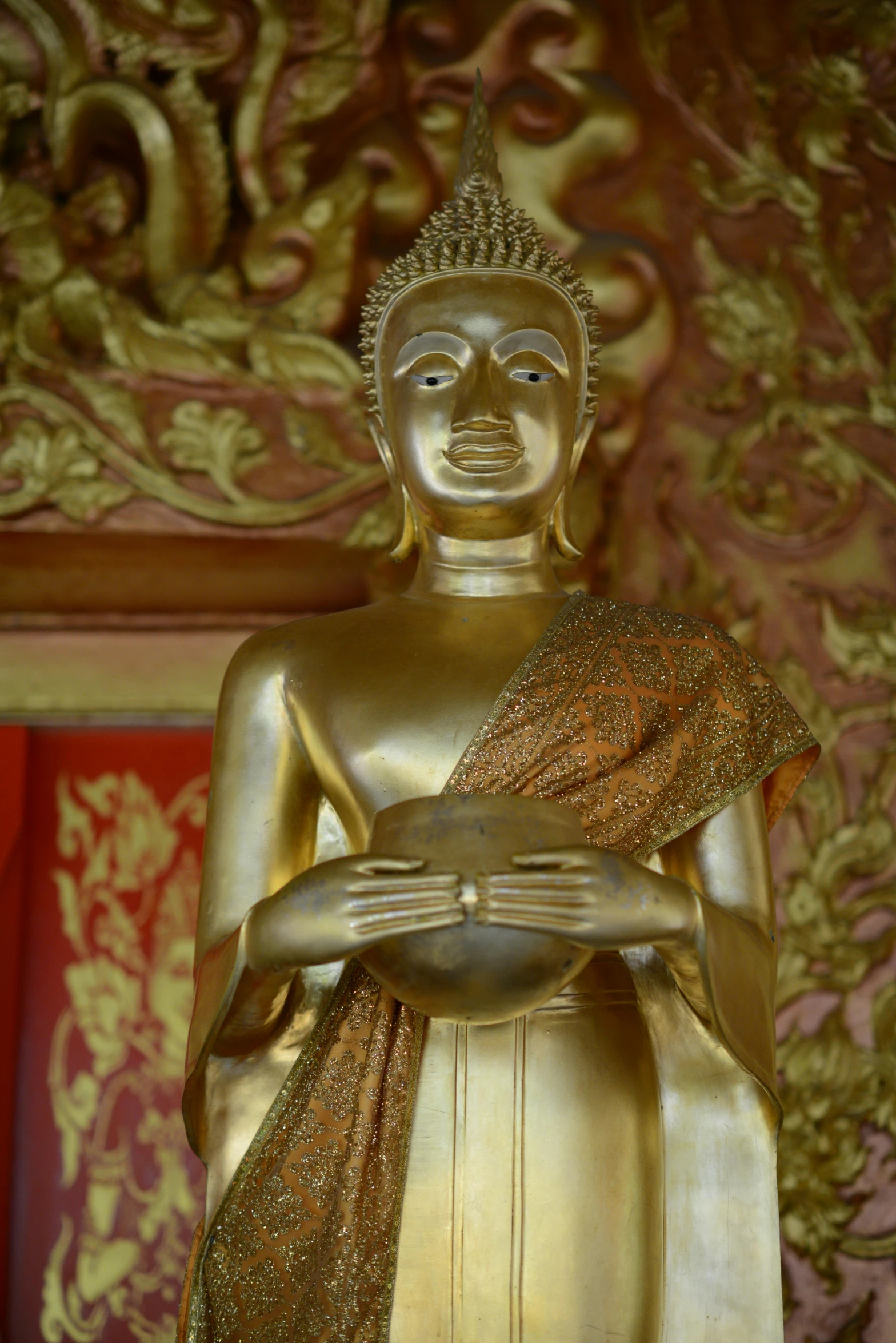 a statue of a person holding a bird, golden robes, the buddha, laos, from inside a temple