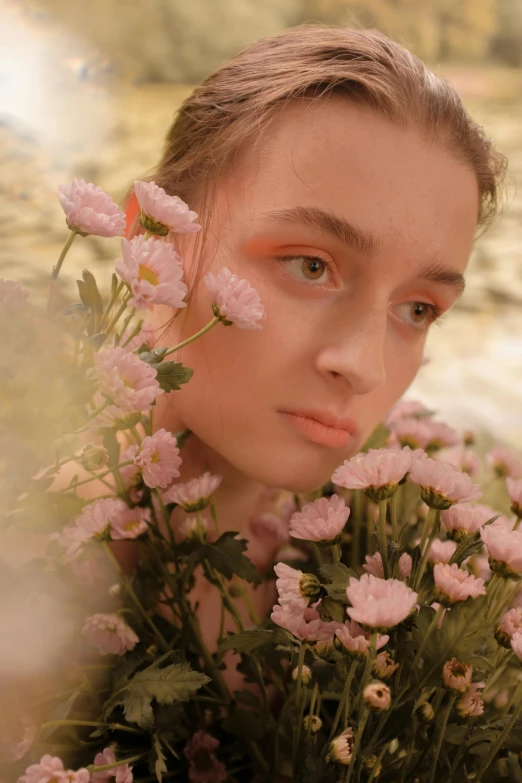 a woman with pink flowers in her hair, inspired by Elsa Bleda, trending on pexels, julia garner, diffused natural skin glow, pale orange colors, natalia dyer