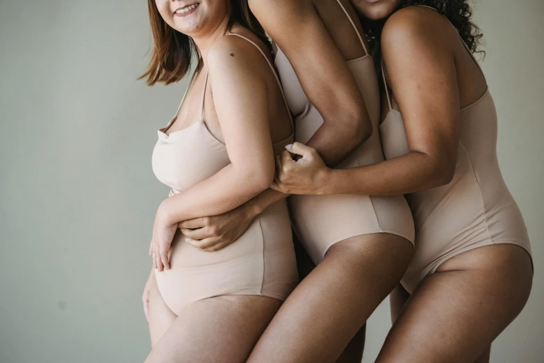 a group of three women standing next to each other, by Matija Jama, trending on pexels, renaissance, stomach skin, neutral colours, wearing leotard, piled around