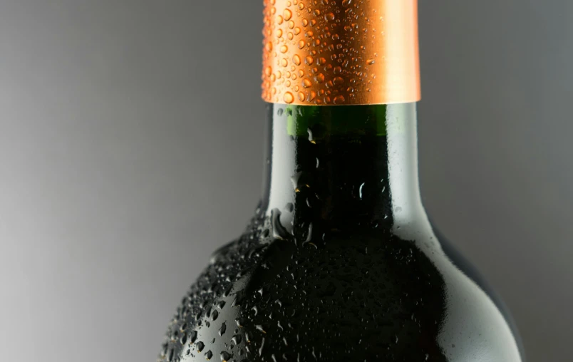 a bottle of wine sitting on top of a table, detailed droplets, on a gray background, thumbnail, up-close