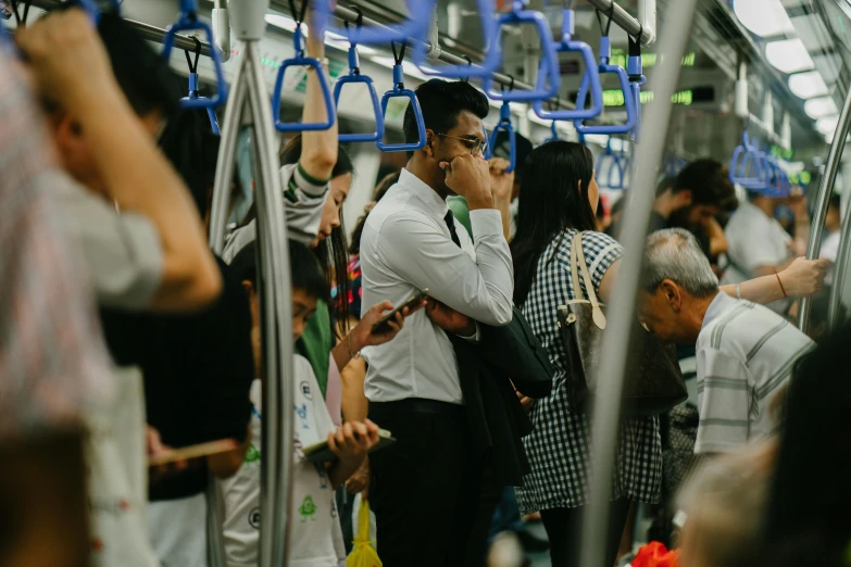 a group of people standing next to each other on a subway, by Carey Morris, pexels contest winner, happening, singapore, hunched shoulders, carriage full of computers, photo of a man