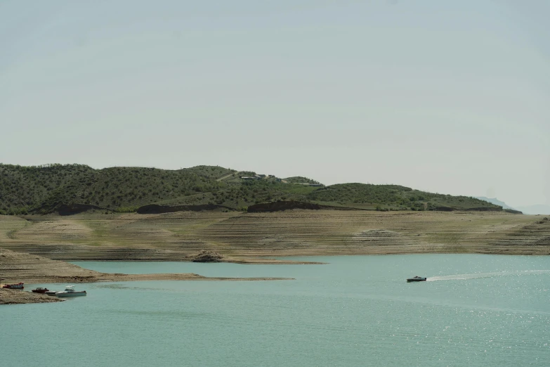 a couple of boats that are in the water, a picture, by Pablo Rey, hurufiyya, water reservoir, 2 0 0 mm wide shot, teal landscape, documentary still