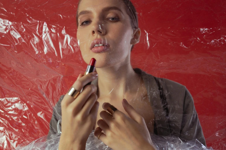 a woman is putting lipstick on her lips, inspired by Elsa Bleda, pexels contest winner, hyperrealism, wearing a plastic garbage bag, in red paint, eleven/millie bobbie brown, promotional image