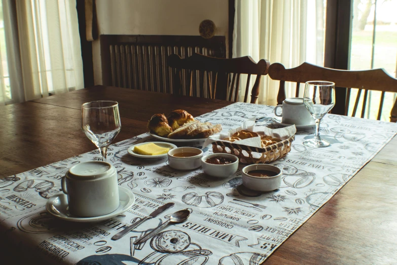 a table topped with plates of food and cups of coffee, inspired by Henri-Julien Dumont, unsplash, tablecloth, arrendajo in avila pinewood, dining room, romanian