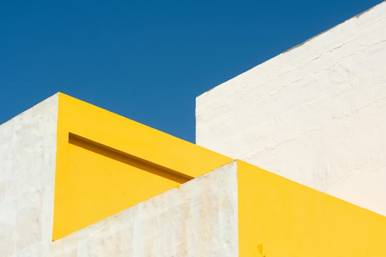 a yellow and white building with a blue sky in the background, a minimalist painting, inspired by Bauhaus, unsplash, minimalism, mexico city, peter guthrie, colors: yellow, ignant
