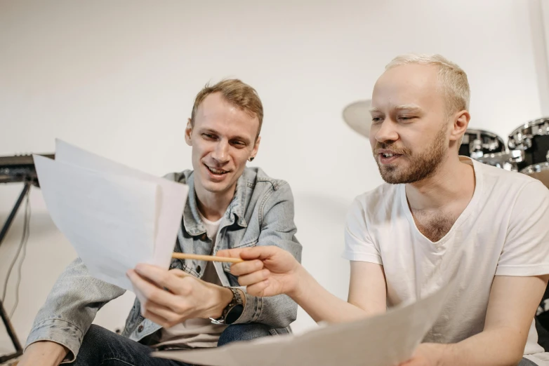 two men sitting on a couch looking at a piece of paper, by Adam Marczyński, pexels contest winner, linus from linustechtips, on a white table, anato finnstark and kelogsloops, promotional image