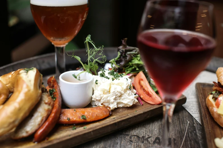 a plate of food and a glass of wine on a table, holding a beer, caulfield, white and red color scheme, boka