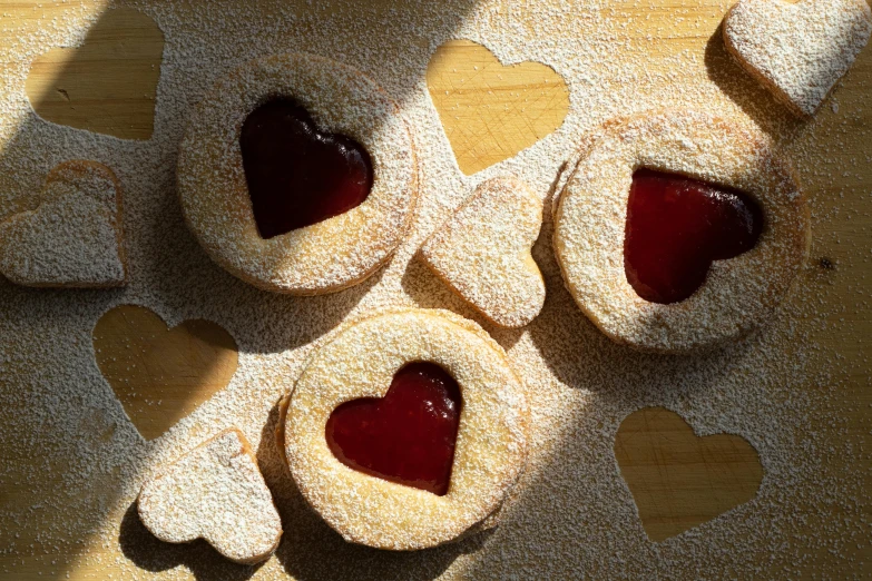 a couple of heart shaped cookies sitting on top of a table, by Sylvia Wishart, trending on pexels, garnet, suns, high angle close up shot, thumbnail