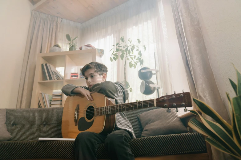 a man sitting on a couch playing a guitar, by Winona Nelson, pexels contest winner, realism, boy staring at the window, timothee chalamet, natural lighting. 8 k, koala playing a guitar