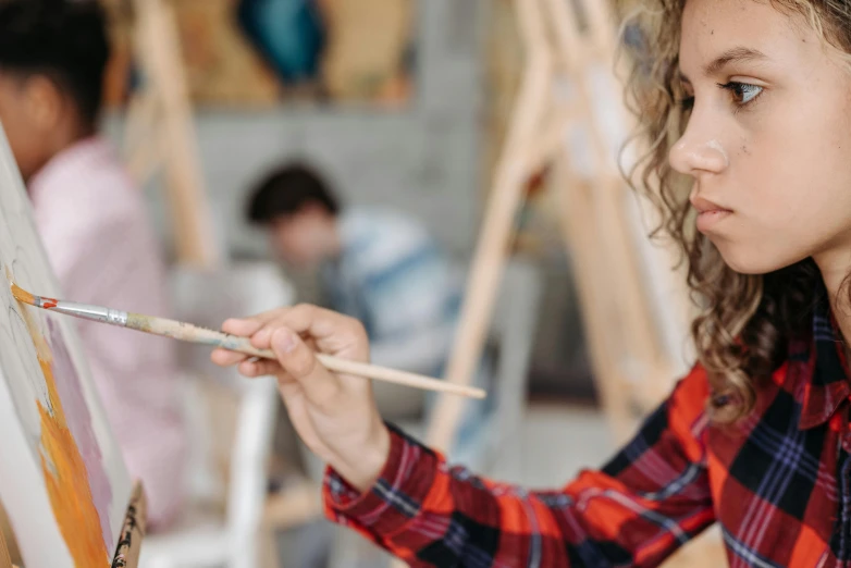 a young girl is painting on an easel, trending on pexels, academic art, looking from shoulder, holding a wooden staff, mate painting, holding pencil