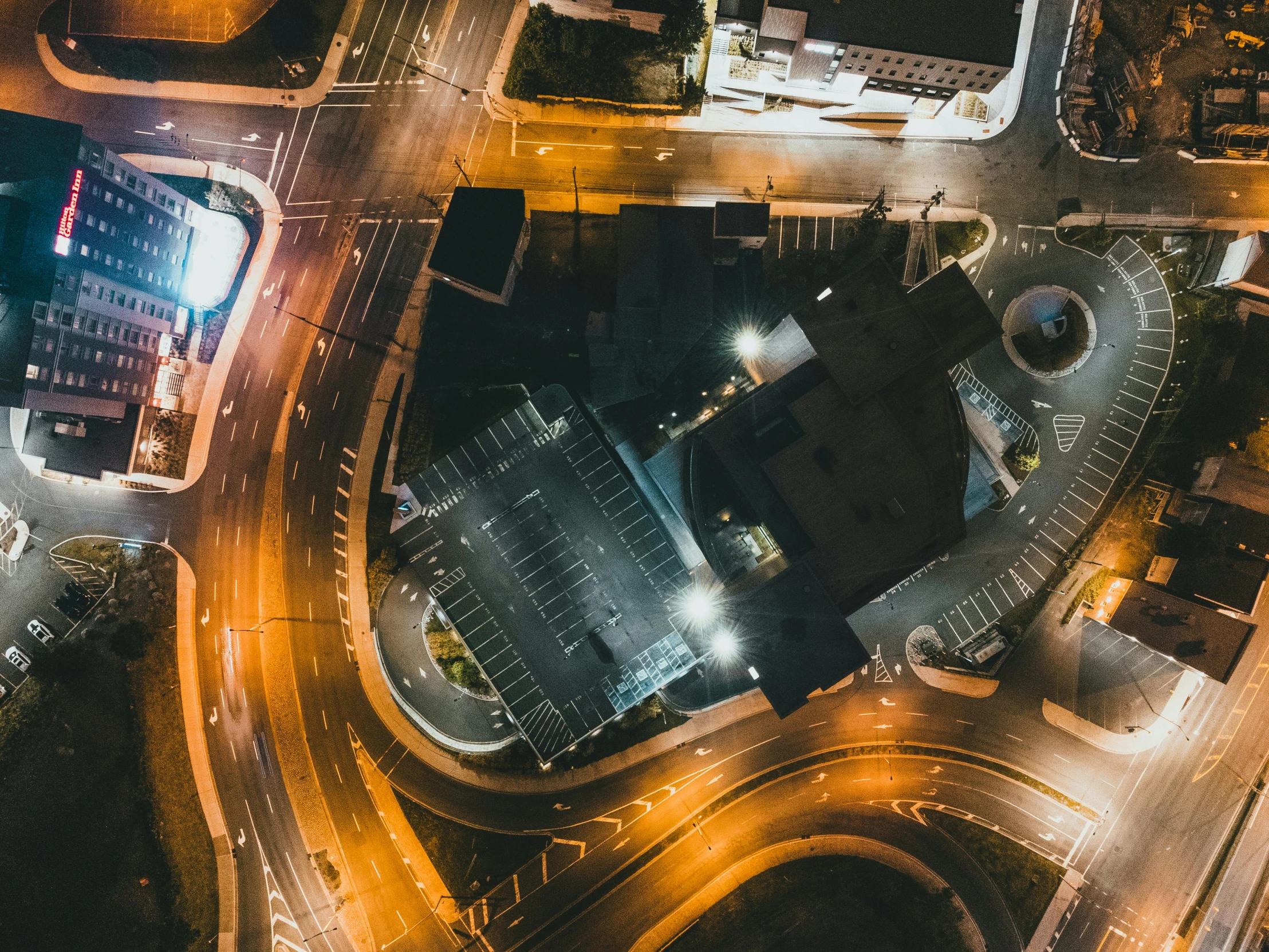 an aerial view of a city at night, by Adam Marczyński, pexels contest winner, intersection, parking lot, thumbnail, square