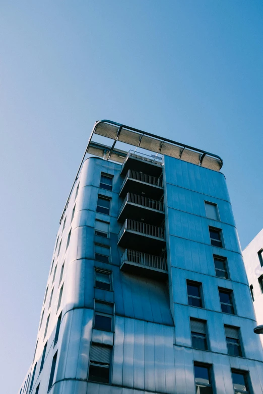 a tall building sitting in the middle of a city, unsplash, modernism, sky blue, iron cladding, apartment, full shot photograph