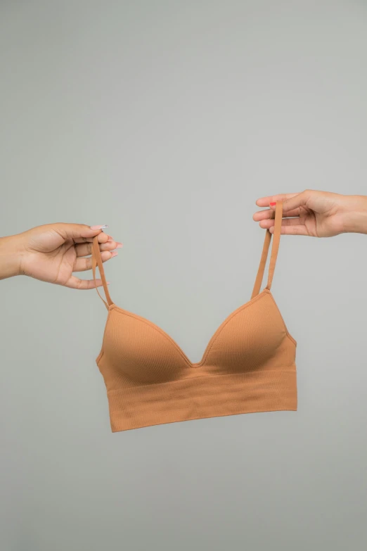 a woman holding a bra in her hands, by Mardi Barrie, unsplash, cinnamon skin color, 155 cm tall, close-up product photo, seamless