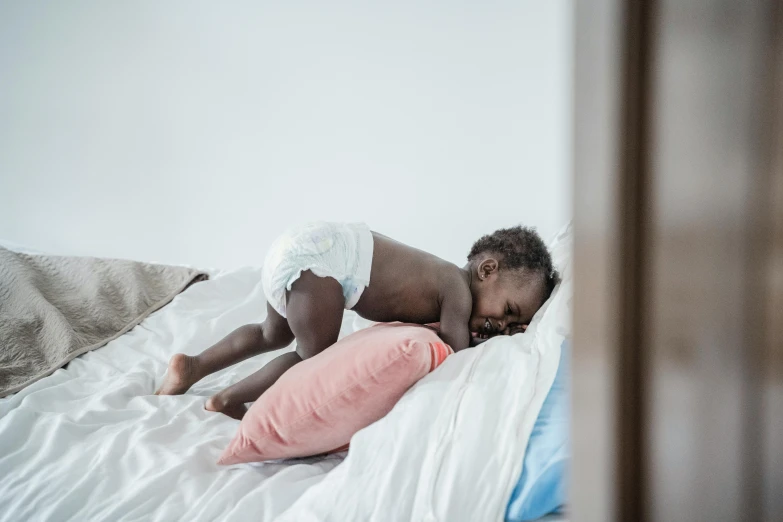 a small child laying on a bed with a pillow, by Matija Jama, pexels contest winner, happening, black skin, hugging his knees, snoring, bouncy belly