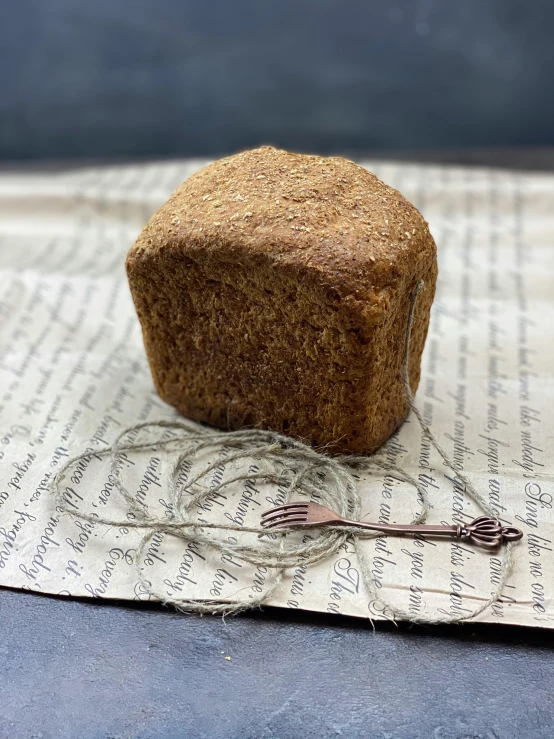 a loaf of bread sitting on top of a piece of paper, menger sponge, handcrafted, rustic, high quality product image”