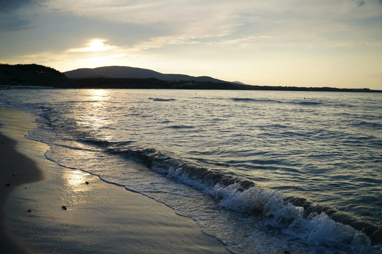 a large body of water sitting on top of a sandy beach, happening, evening sun, beachfront, splashing, greece