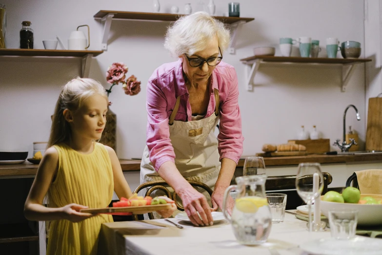 a woman standing next to a little girl in a kitchen, inspired by Elsa Beskow, pexels contest winner, at a dinner table, clay animation, an elderly, ceramics