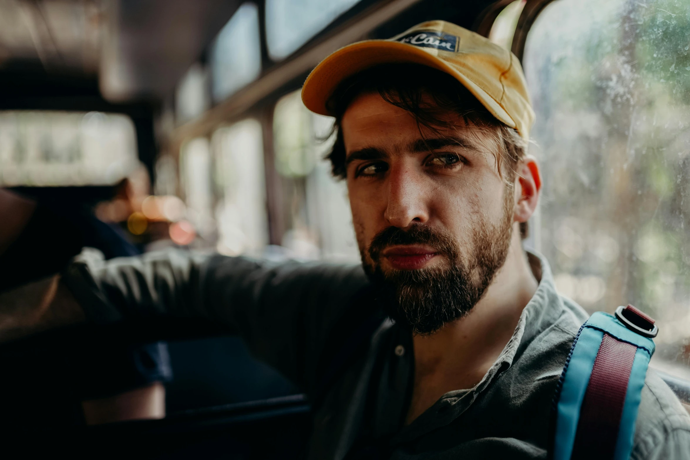 a close up of a person wearing a hat, by Adam Marczyński, pexels contest winner, photorealism, bearded beautiful man, yellow cap, lofi portrait at a window, young greek man