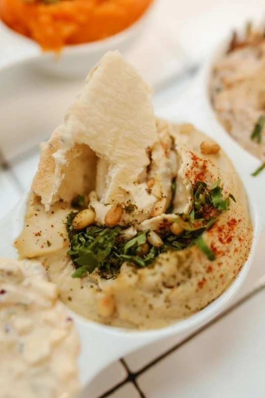 a white plate topped with hummus and pita chips, by Emanuel Witz, pexels, renaissance, slide show, dumplings on a plate, blurred detail, cut-away