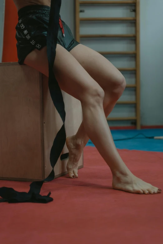 a woman sitting on top of a box next to a cat, inspired by Elizabeth Polunin, trending on pexels, arabesque, hand wraps, in a gym, ribbon, cinematic still frame