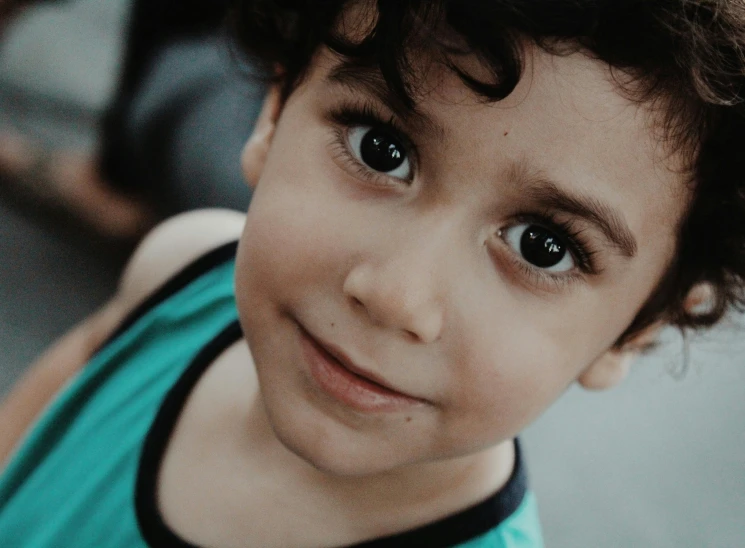 a close up of a child looking at the camera, teal eyebrows, small smile, black hair and large eyes, boy with neutral face