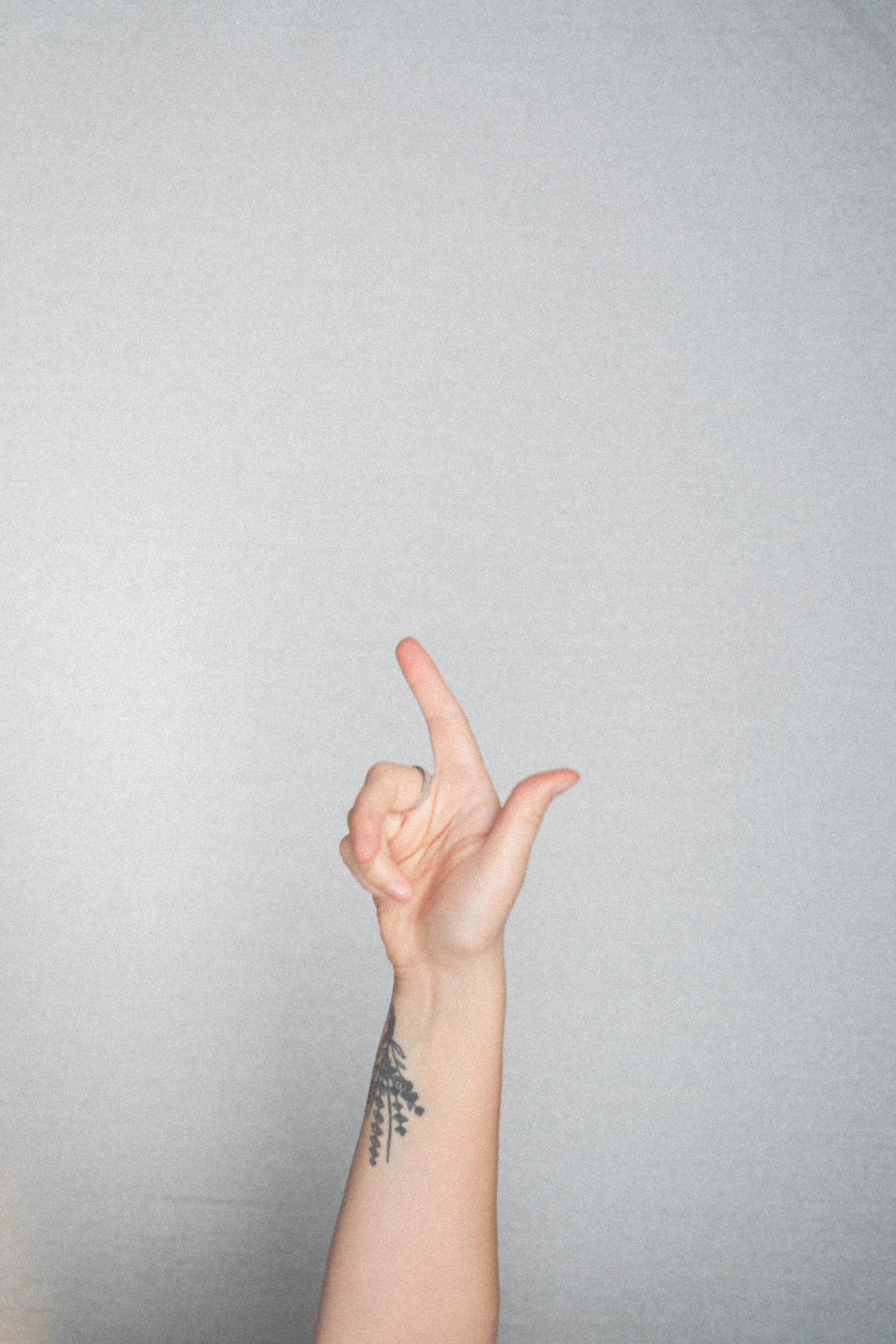 a woman making a peace sign with her fingers, a tattoo, trending on pexels, realism, grey backdrop, h3h3, non binary model, thumb up