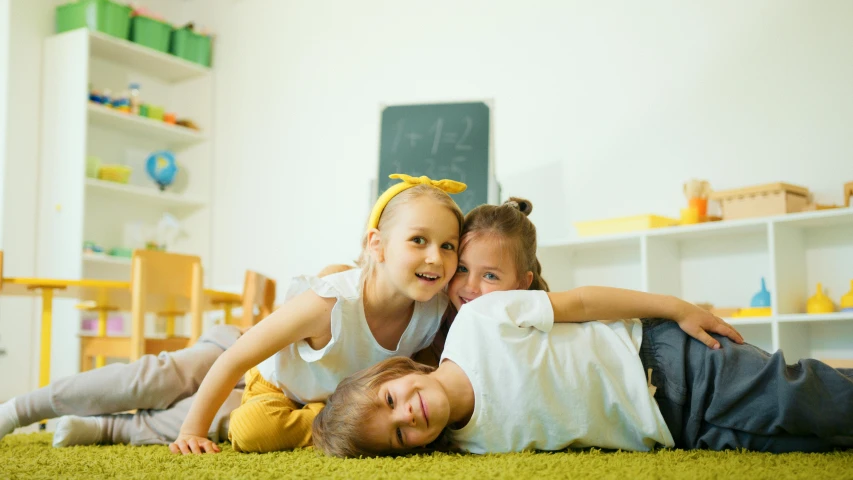 a couple of kids laying on top of each other, a picture, by Adam Marczyński, shutterstock, photo of a classroom, yellow carpeted, 15081959 21121991 01012000 4k, group photo