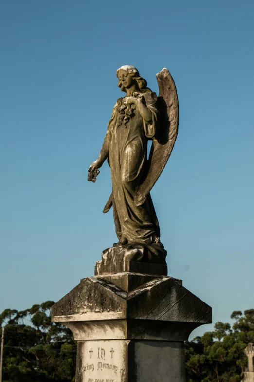 a statue of an angel in a cemetery, inspired by Edwin Deakin, southern cross, view from the side