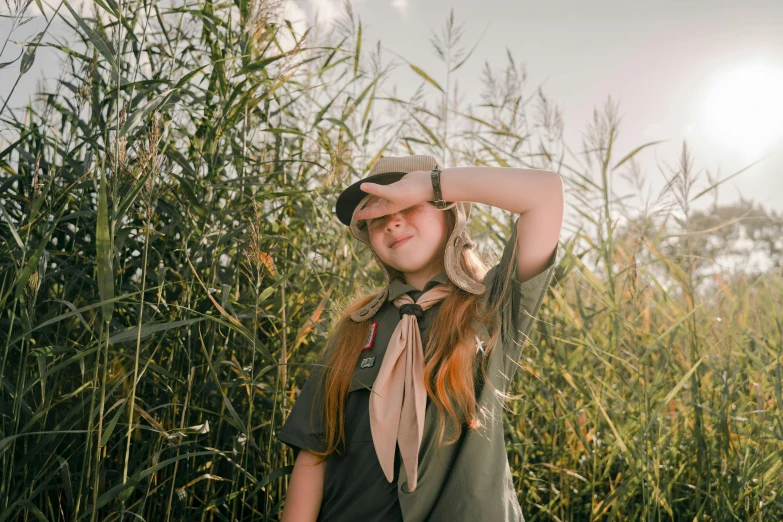 a woman standing in a field of tall grass, a picture, trending on unsplash, girl wearing uniform, scout boy, avatar image, wearing a headband