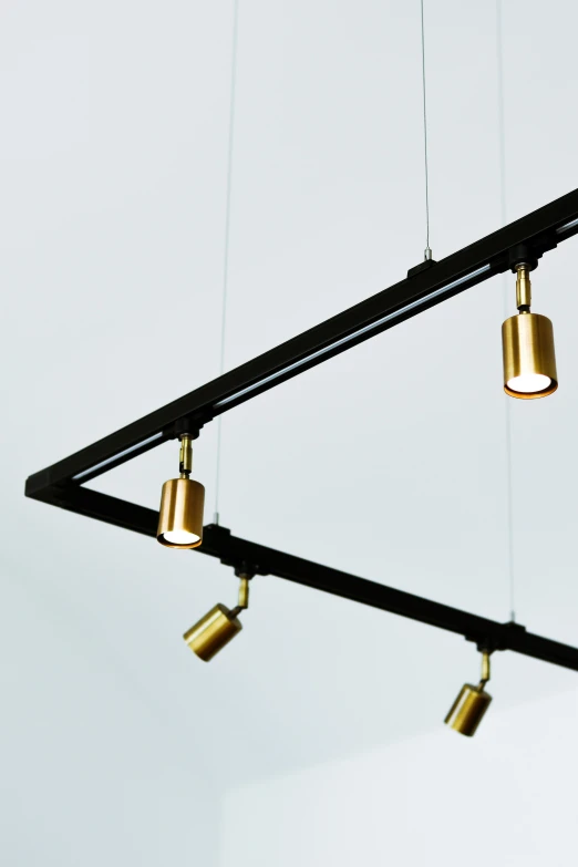 a black and gold chandelier hanging from a ceiling, inspired by Anton Möller, minimalism, technical detail, spot lighting, light frame, 3 point lighting