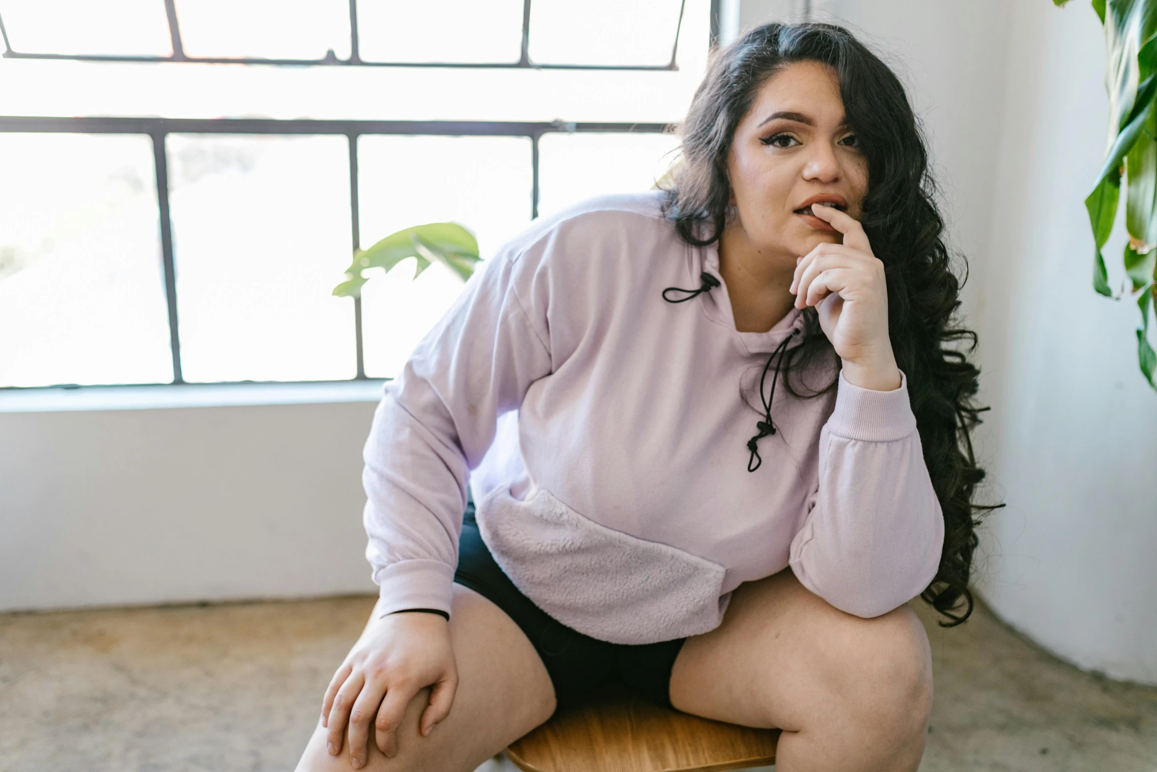 a woman sitting on top of a wooden chair, inspired by Esaias Boursse, trending on pexels, realism, wearing a pastel pink hoodie, her belly is fat and round, bra and shorts streetwear, lilac