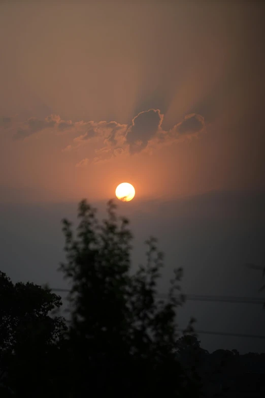 the sun is setting in the sky over the trees, a picture, flickr, smoke billows over the horizon, atmospheric ”