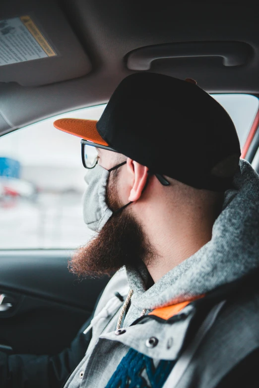 a man with a beard sitting in a car, black and orange, wearing facemask, discord profile picture, car commercial photograph