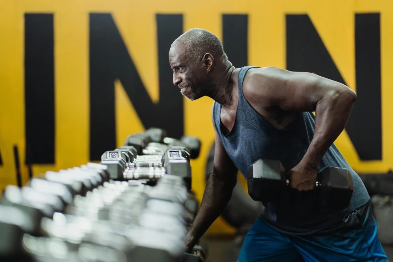 a man lifting dumbbells in a gym, a photo, by Lisa Nankivil, black and yellow, an 9 4, niea 7, profile image