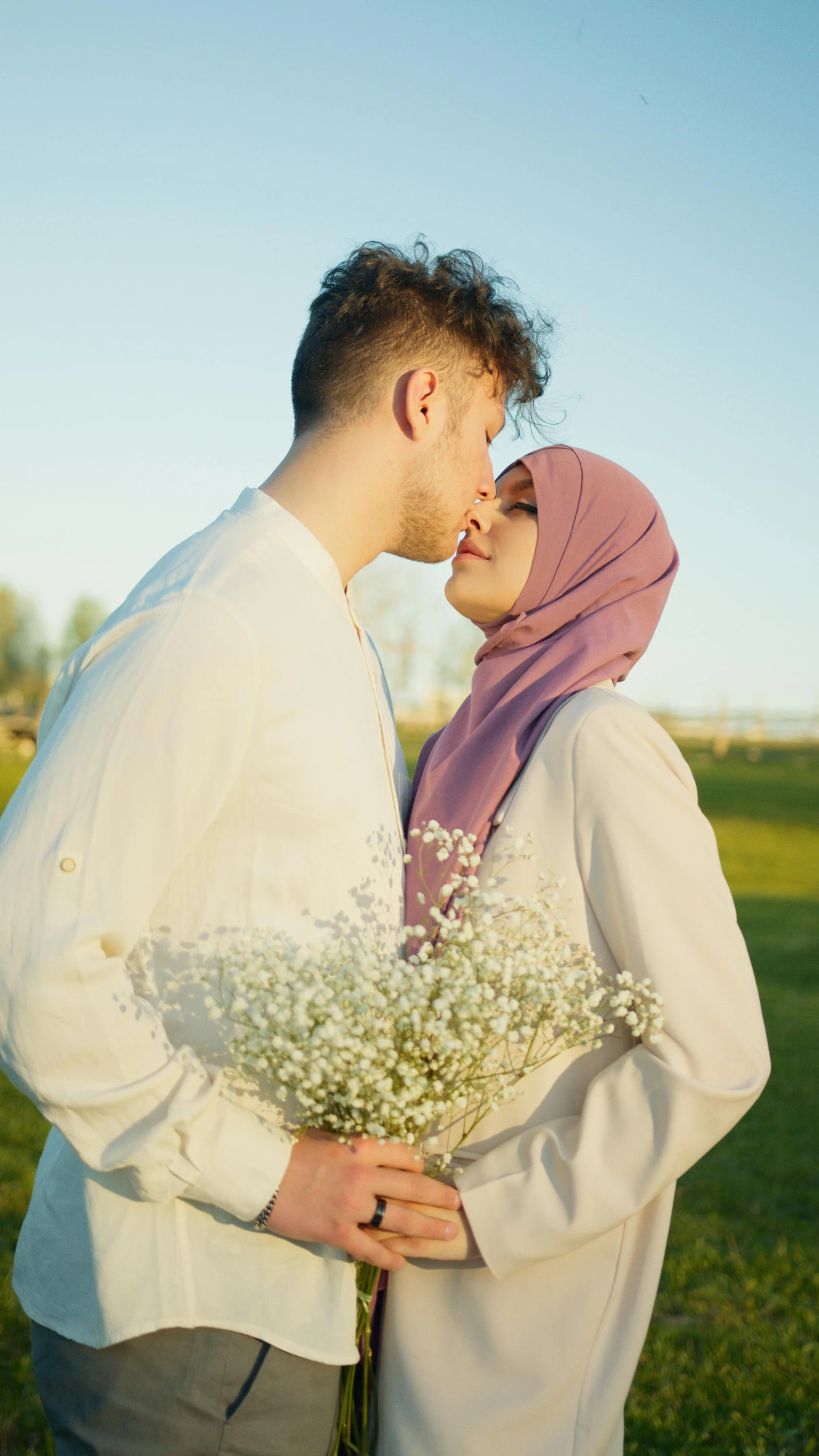 a man standing next to a woman holding a bouquet of flowers, a colorized photo, shutterstock, hurufiyya, kissing each other, white hijab, 15081959 21121991 01012000 4k, sunny environment