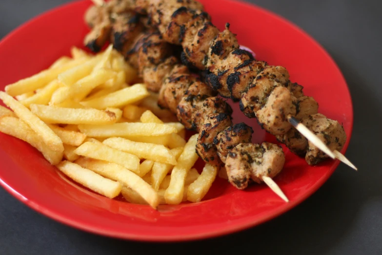 a red plate topped with kebabs and french fries, hurufiyya, grilled chicken, thumbnail, black stripes, australian