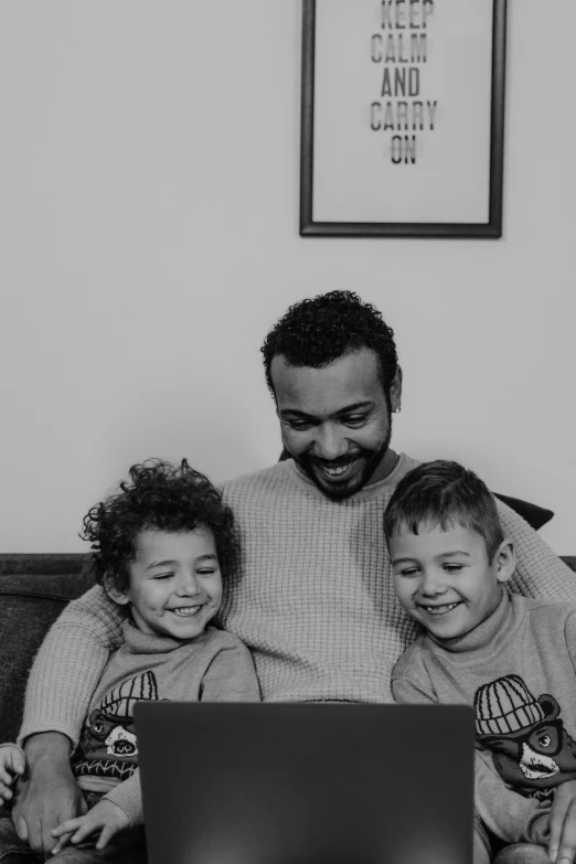 a man and two children sitting on a couch with a laptop, a black and white photo, by Sam Charles, pexels contest winner, mo salah, childish gambino, hearts, panel