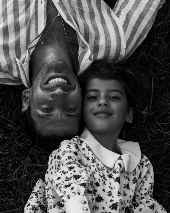 a black and white photo of two people laying in the grass, by irakli nadar, unsplash contest winner, caring fatherly wide forehead, smiling at the camera, peter hurley, vogue italia