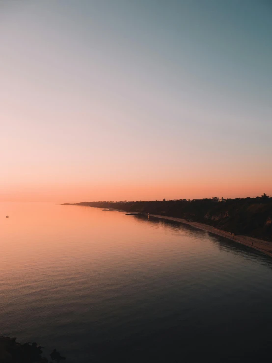 the sun is setting over a body of water, a picture, by Ryan Pancoast, unsplash contest winner, minimalism, wide high angle view, lachlan bailey, clear skies in the distance, calmly conversing 8k