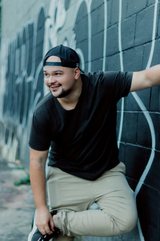 a man leaning against a wall with a skateboard, headshot profile picture, plus size, dark. no text, joyful smirk