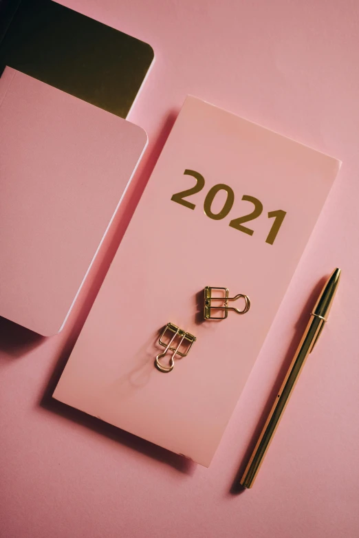 a notepad sitting on top of a desk next to a laptop, by Julia Pishtar, trending on pexels, happening, new years eve, gradient pink, thumbnail, from star trek 2021