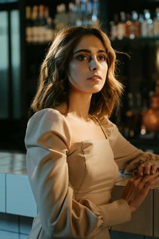 a woman in a beige dress sitting at a bar, inspired by Elsa Bleda, trending on pexels, emma watson, square, low iso, maya ali