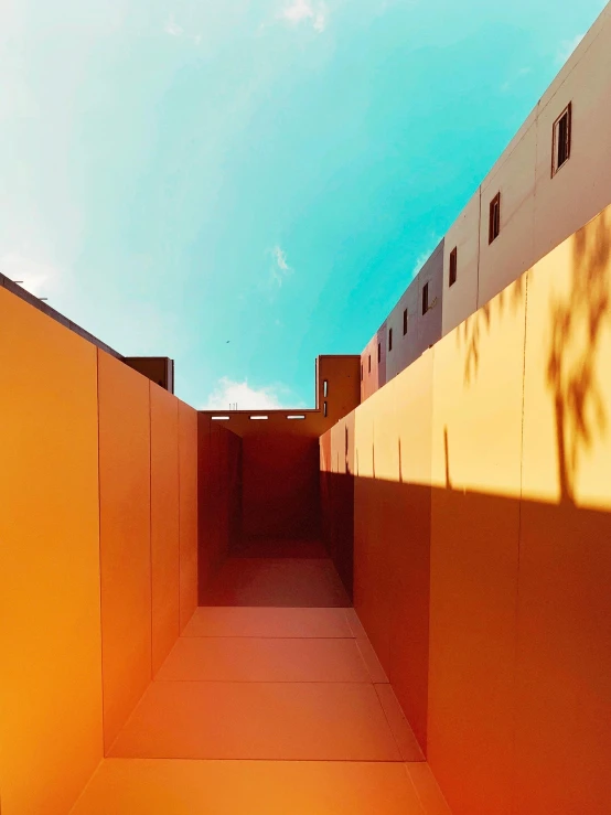 an orange building with a blue sky in the background, inspired by Ricardo Bofill, unsplash contest winner, color field, courtyard walkway, volumetric light and shadow, panoramic anamorphic, snapchat photo